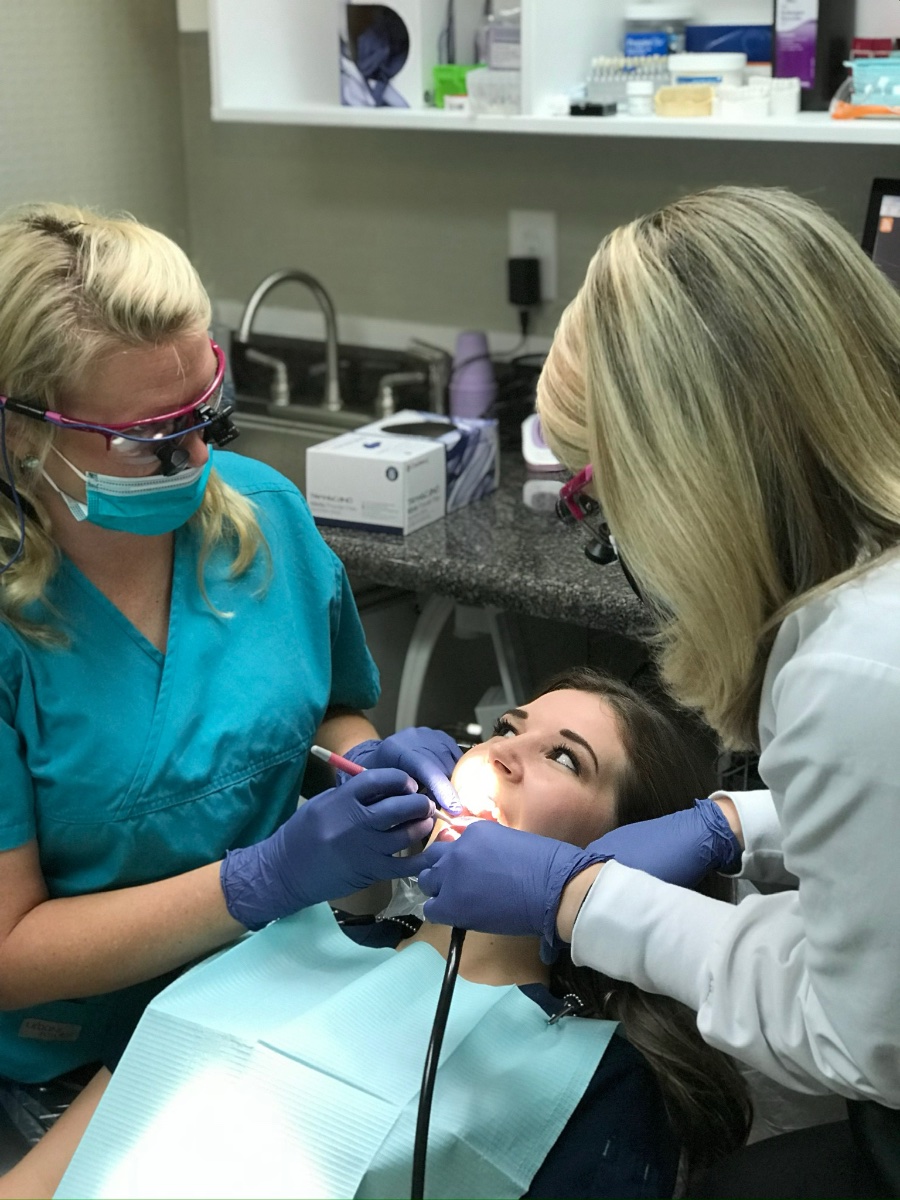 Dental assistants working on patient during general dentistry procedure for comprehensive care.