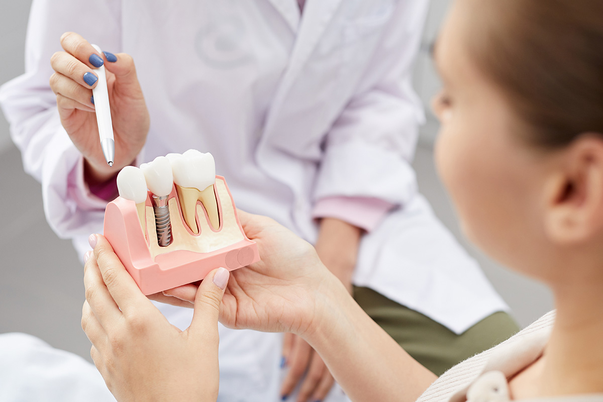A dentist showing a patient a dental implant model